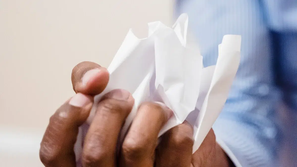 Eine Hand hält fest ein zerknülltes Blatt Papier.