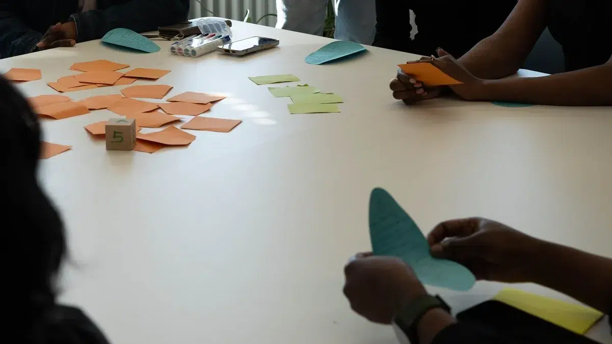 Mehrere Menschen arbeiten gemeinsam mit Karten an einem Tisch.