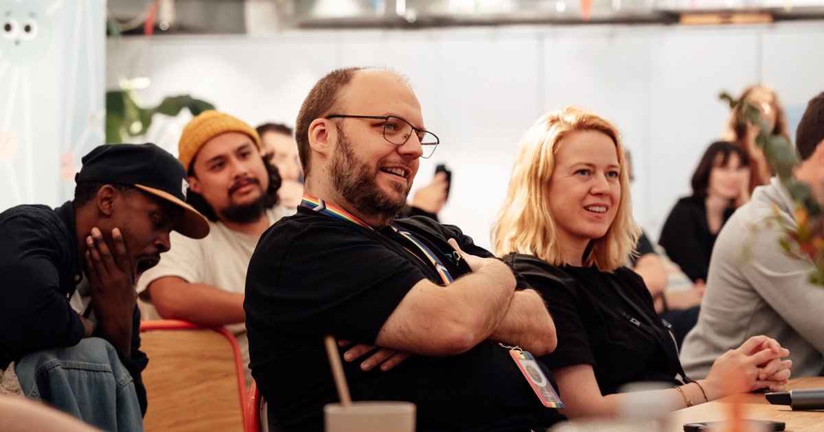 Lächelnde Teilnehmer bei Konferenz oder Meetup hören aufmerksam einem Vortrag zu, im Gespräch mit Kollegen.