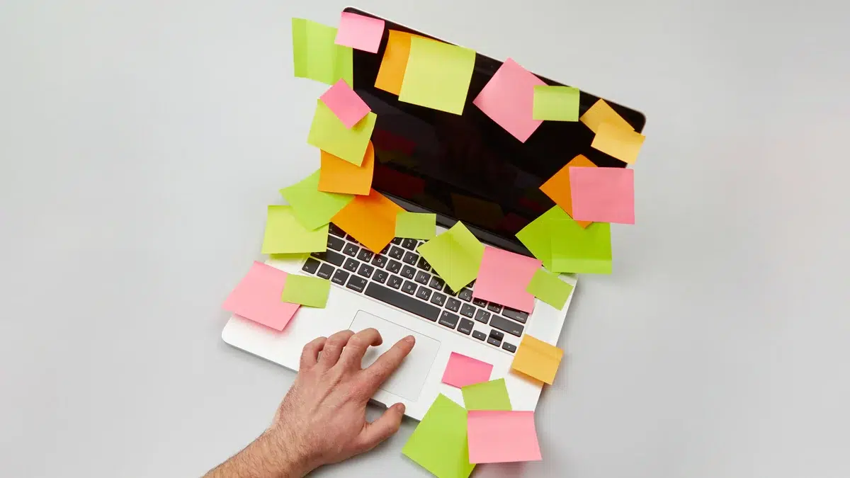 Ein Laptop ist von zahlreichen bunten Haftnotizen bedeckt.