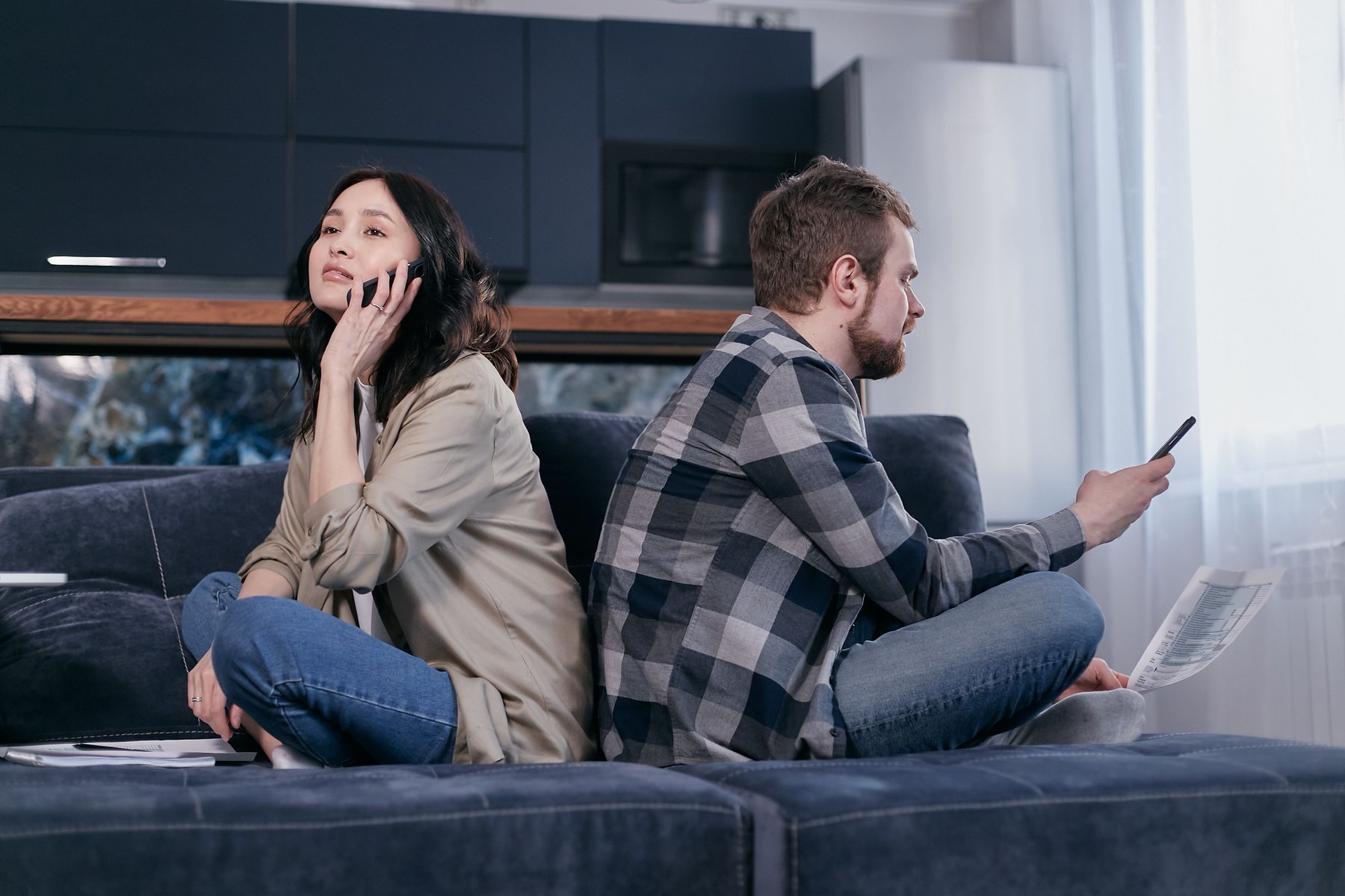Zwei voneinander abgewandte Menschen sitzen auf einem Sofa und schauen auf ihre Smartphones.