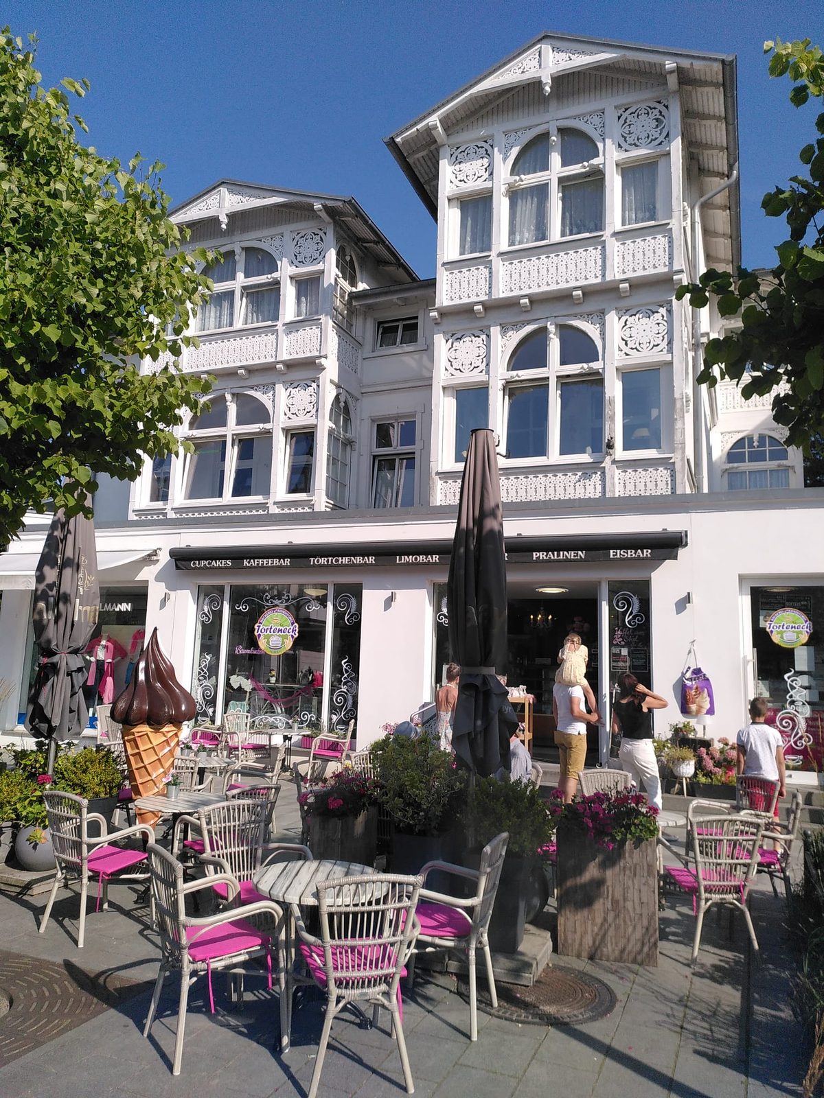 Bäderarchitektur in einem Ostseebad auf Rügen, weiße Villa mit Holzveranden und Caféstühlen davor