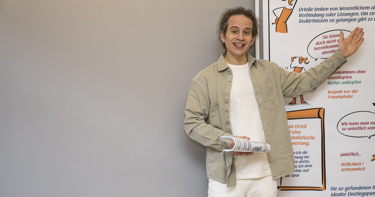Ein Trainer zeigt auf ein Flipchart mit der Überschrift Urteile übersetzen, Bedürfnisse entdecken.